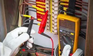 Electrician testing a distribution board with a multimeter in Singapore